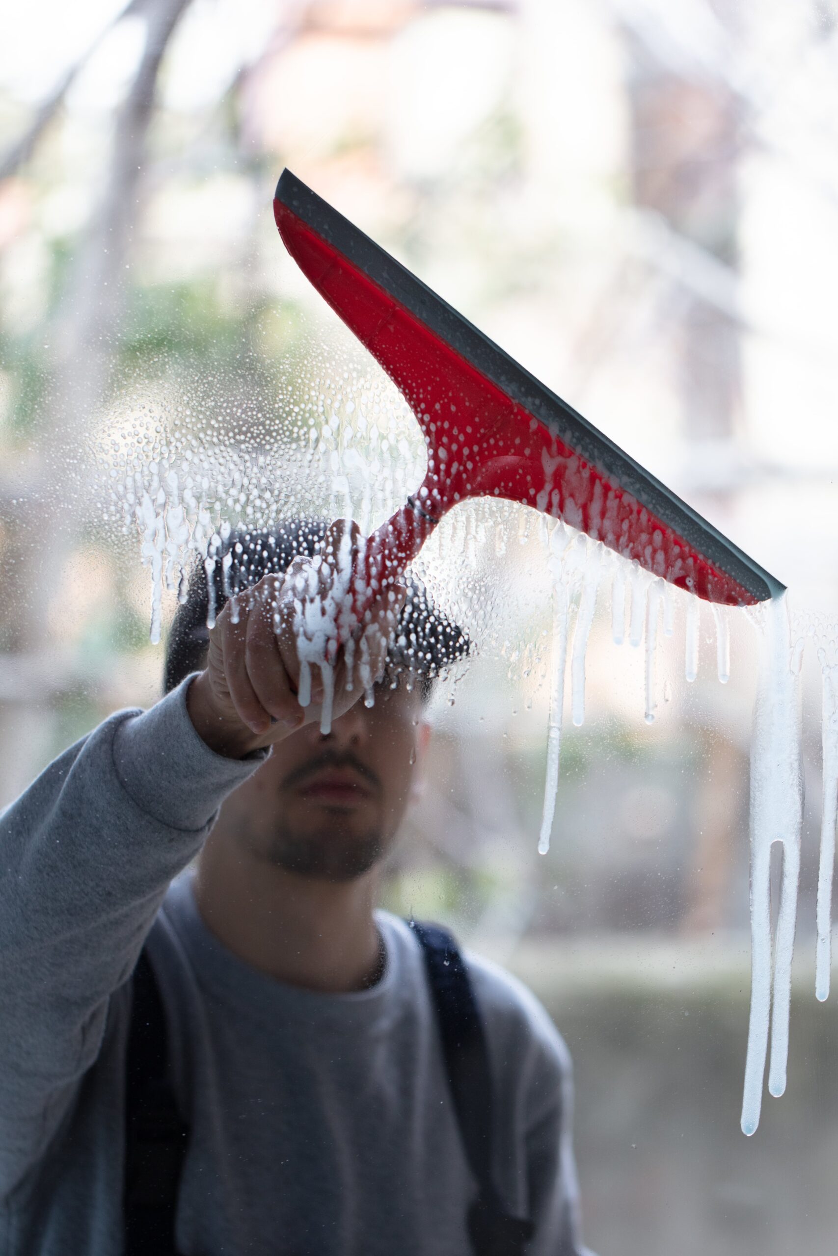 closeup-person-cleaning-windows-with-red-squeegee-min